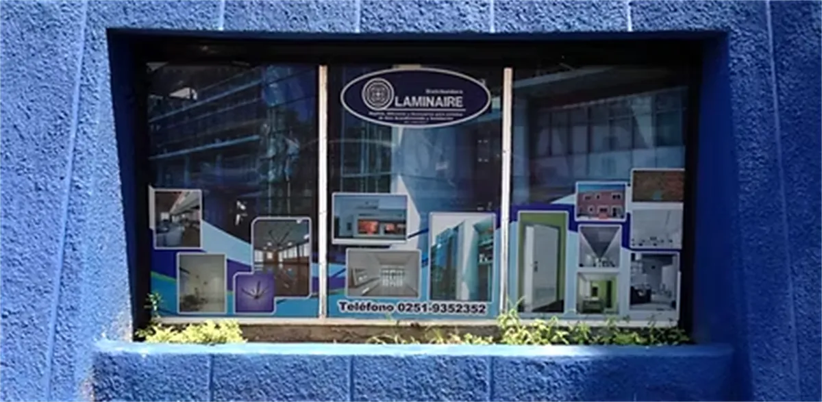 Vitrina del local de Laminaire en una fachada azul, con muestras de productos y el logo de la empresa
